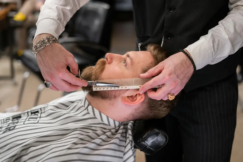 Barber upravuje vousy klientovi břitvou